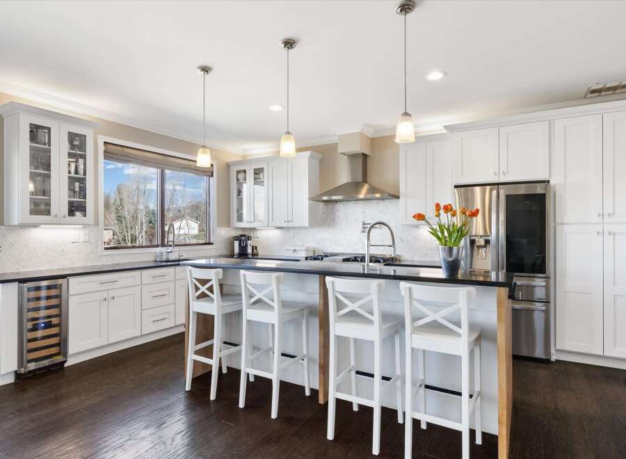 This stunning kitchen boasts a modern design with sleek white cabinetry and a spacious island, perfect for both cooking and entertaining.
