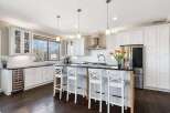 This stunning kitchen boasts a modern design with sleek white cabinetry and a spacious island, perfect for both cooking and entertaining.