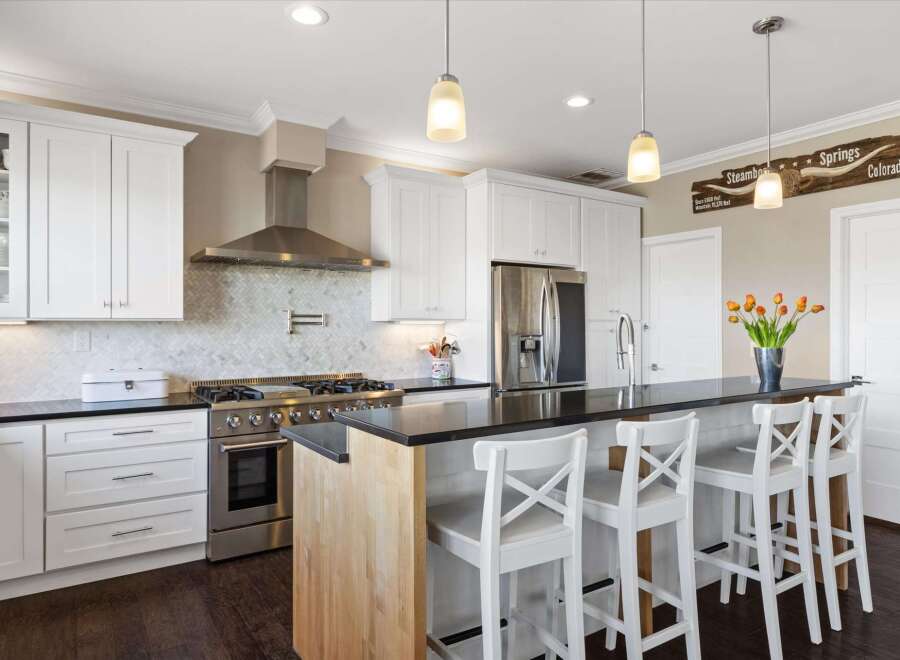 This stunning kitchen boasts a modern design with sleek white cabinetry and a contrasting black countertop.