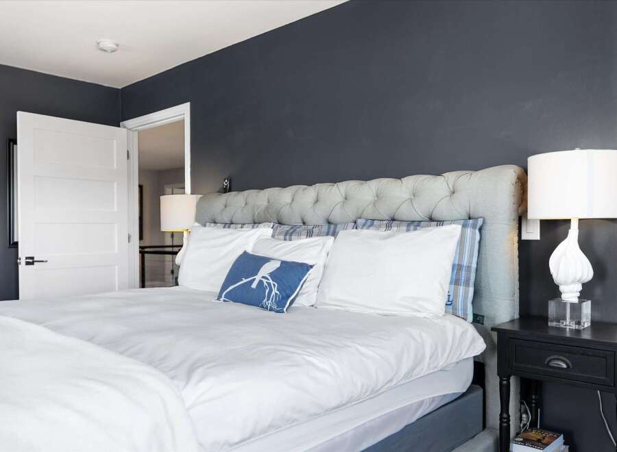 This stunning bedroom boasts a luxurious tufted headboard and plush bedding, creating a serene and inviting atmosphere.