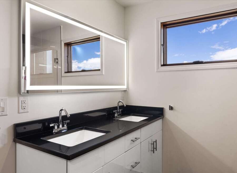 This stunning bathroom features a modern design with a sleek black countertop and a double sink vanity.