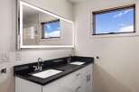 This stunning bathroom features a modern design with a sleek black countertop and a double sink vanity.
