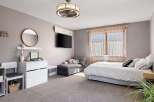 Step into this inviting bedroom, featuring a cozy chaise lounge, a stylish entertainment setup, and a comfortable bed.