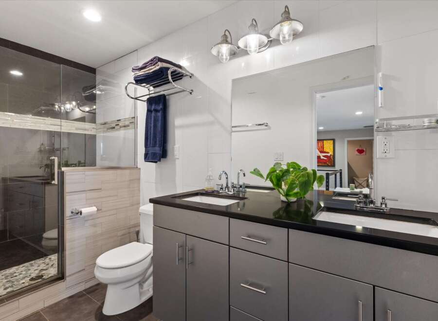Step into modern luxury with this stunning bathroom! Featuring sleek gray cabinetry, a black countertop, and a double sink, this space is both stylish and functional.