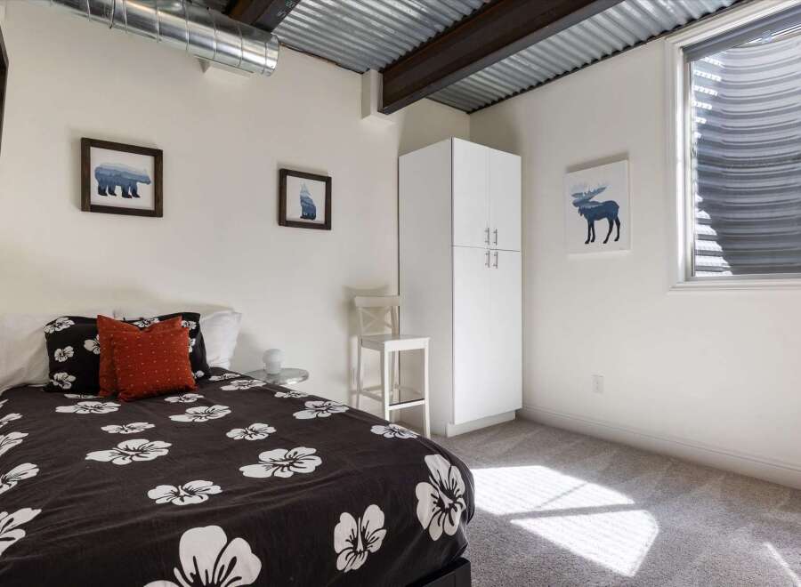 This cozy bedroom features a unique corrugated metal ceiling and exposed beams, adding a touch of industrial charm.