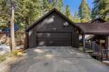 Nestled amidst towering trees, this charming property boasts a striking black exterior and a welcoming garage.