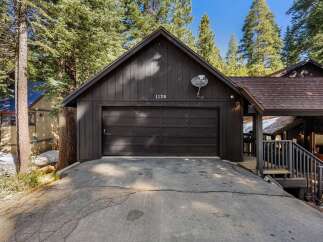 Nestled amidst towering trees, this charming property boasts a striking black exterior and a welcoming garage.