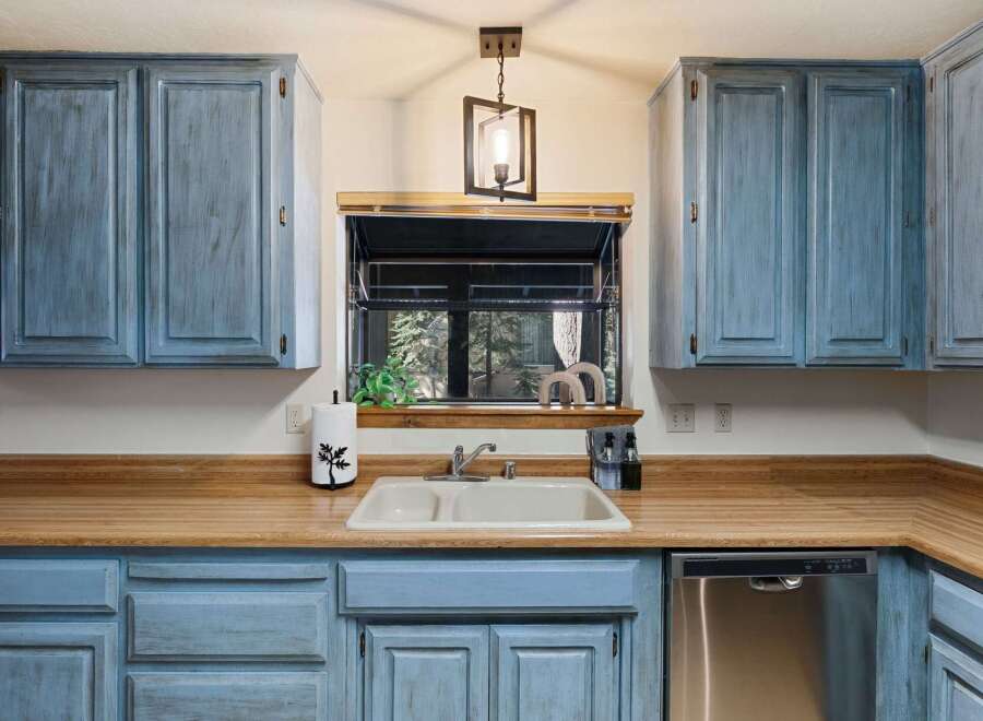 This charming kitchen features beautiful blue cabinetry and a warm wooden countertop, creating a cozy and inviting atmosphere.