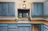 This charming kitchen features beautiful blue cabinetry and a warm wooden countertop, creating a cozy and inviting atmosphere.