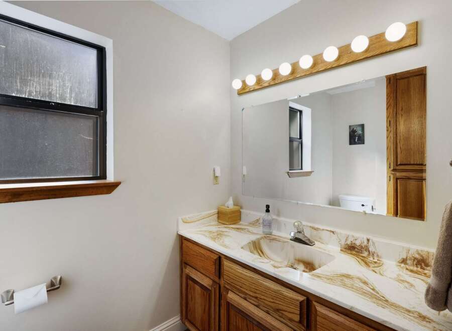 This bathroom features a stylish vanity with a unique countertop design and wooden cabinets.