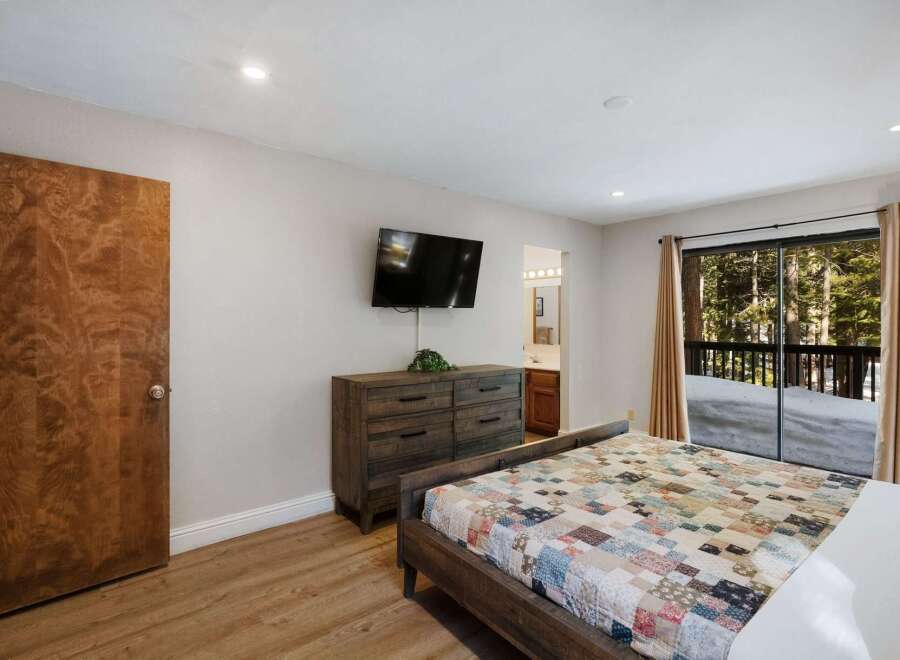 This cozy bedroom features a rustic wooden dresser and a mounted TV, perfect for relaxing after a day of exploring.