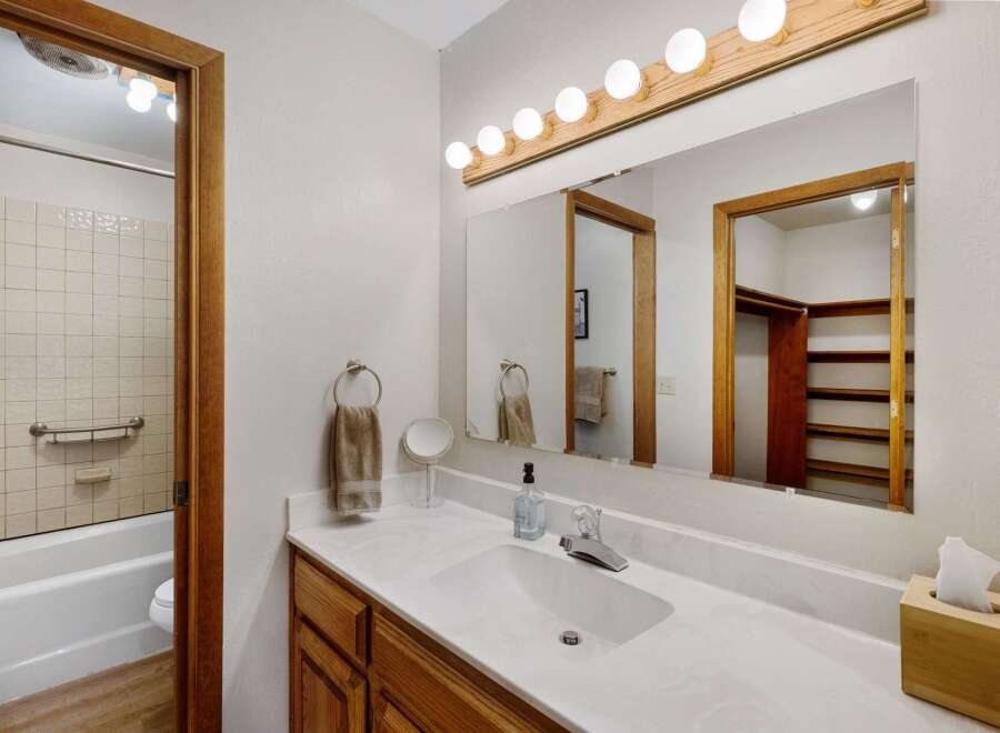 This inviting bathroom features a bright vanity area with a large mirror and ample lighting.