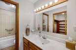 This inviting bathroom features a bright vanity area with a large mirror and ample lighting.