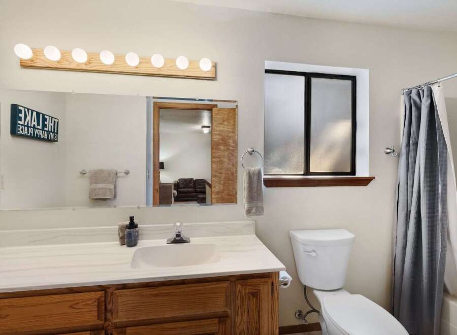 This inviting bathroom features a well-lit vanity area with a large mirror and stylish lighting fixtures.