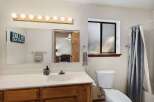 This inviting bathroom features a well-lit vanity area with a large mirror and stylish lighting fixtures.