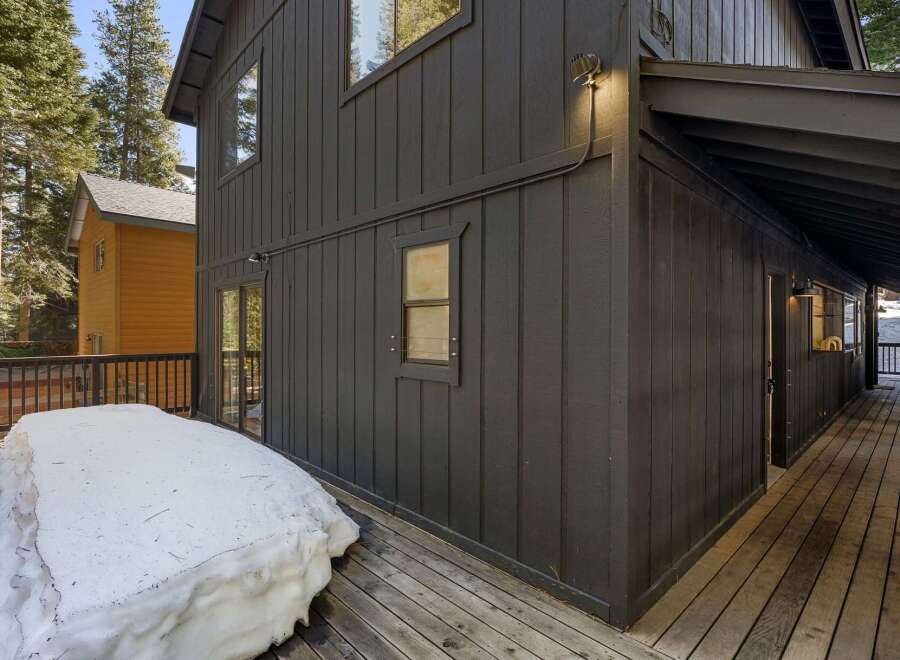 This stunning property boasts a modern exterior with dark siding and a spacious deck, perfect for enjoying the outdoors.