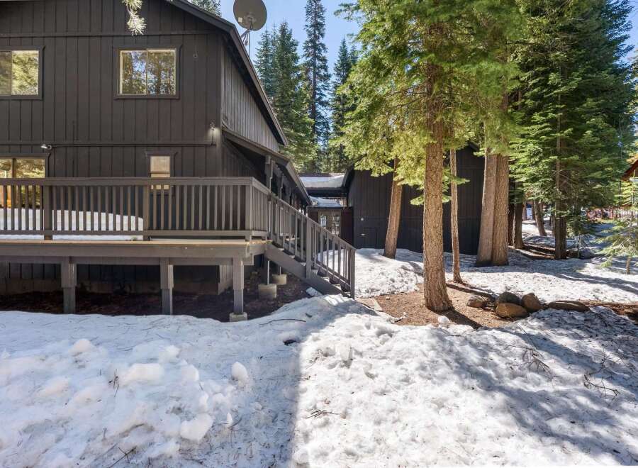 Nestled amidst towering trees, this stunning property boasts a dark exterior and a spacious deck, perfect for enjoying the serene surroundings.