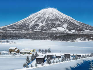 Nestled in a serene winter wonderland, this property offers stunning views of a snow-capped mountain and a pristine, frozen lake.