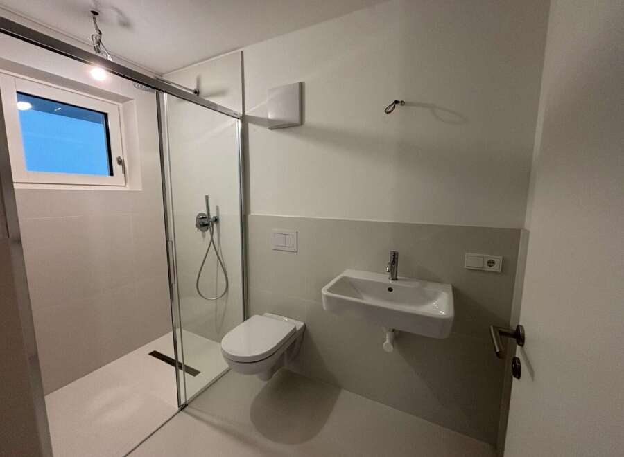 Step into this modern bathroom, featuring a sleek glass shower enclosure and contemporary fixtures.