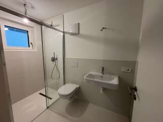 Step into this modern bathroom, featuring a sleek glass shower enclosure and contemporary fixtures.