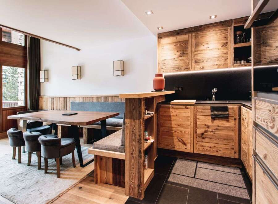 Experience rustic elegance in this stunning property! This kitchen features custom wooden cabinetry, a sleek black countertop, and a cozy dining area with a built-in bench.