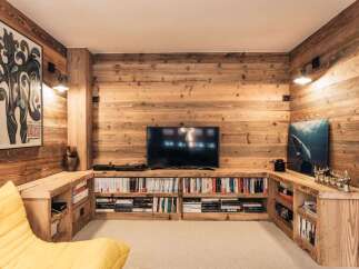 This stunning living room boasts a rustic, inviting ambiance with its warm wooden paneling and built-in shelving.