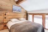 This cozy bedroom features a rustic wooden wall and a comfortable bed, perfect for a relaxing getaway.