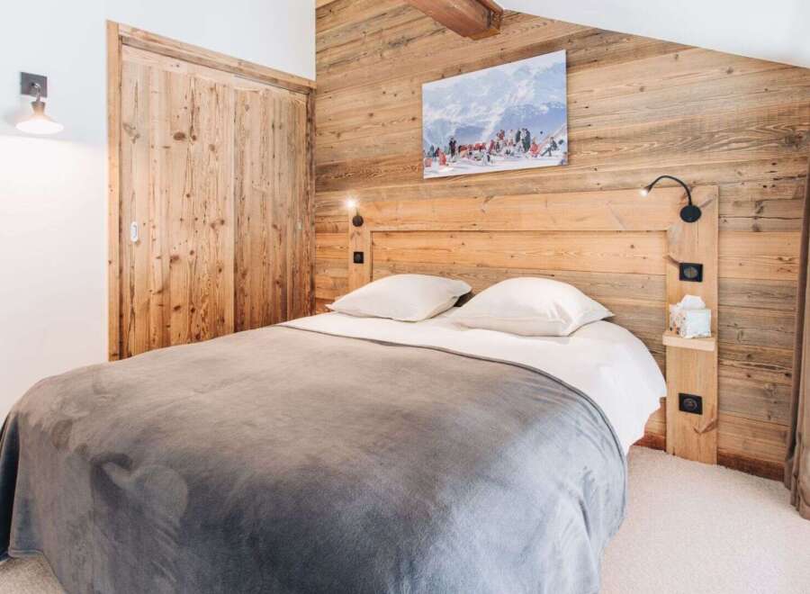 Experience rustic charm in this cozy bedroom, featuring a stunning wooden headboard and paneling that exudes warmth.