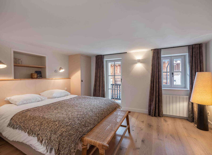 This cozy bedroom features a comfortable bed with a stylish throw blanket, perfect for a relaxing retreat.