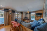 Experience the warmth of this stunning chalet, featuring a cozy living area with a fireplace and a comfortable seating arrangement.