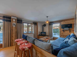 Experience the warmth of this stunning chalet, featuring a cozy living area with a fireplace and a comfortable seating arrangement.