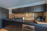 This modern kitchen boasts sleek black cabinetry and a stunning wooden backsplash, creating a stylish and inviting space.