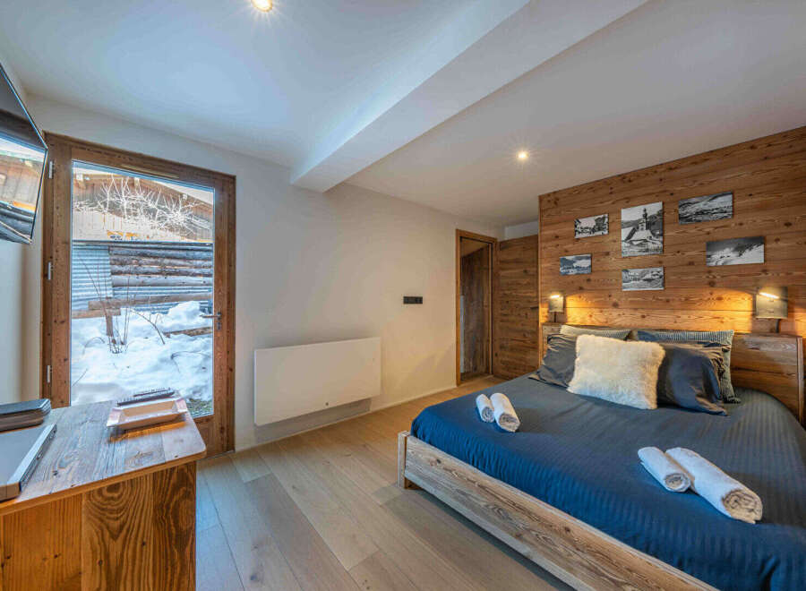 Experience the ultimate comfort in this cozy bedroom, featuring a rustic wooden accent wall and a plush bed.