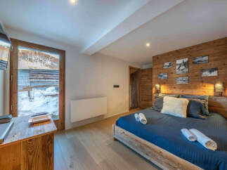 Experience the ultimate comfort in this cozy bedroom, featuring a rustic wooden accent wall and a plush bed.