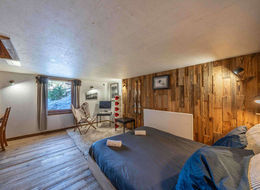 Discover the charm of this cozy bedroom, featuring a unique wooden accent wall and a comfortable bed.