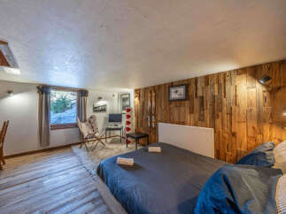 Discover the charm of this cozy bedroom, featuring a unique wooden accent wall and a comfortable bed.