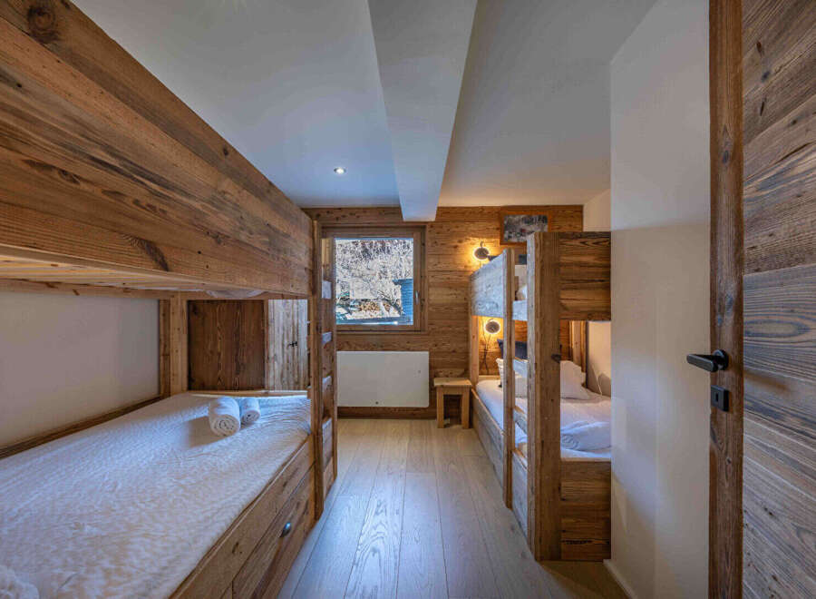 This cozy bedroom features custom-built bunk beds with wooden frames, perfect for accommodating multiple guests.