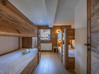 This cozy bedroom features custom-built bunk beds with wooden frames, perfect for accommodating multiple guests.