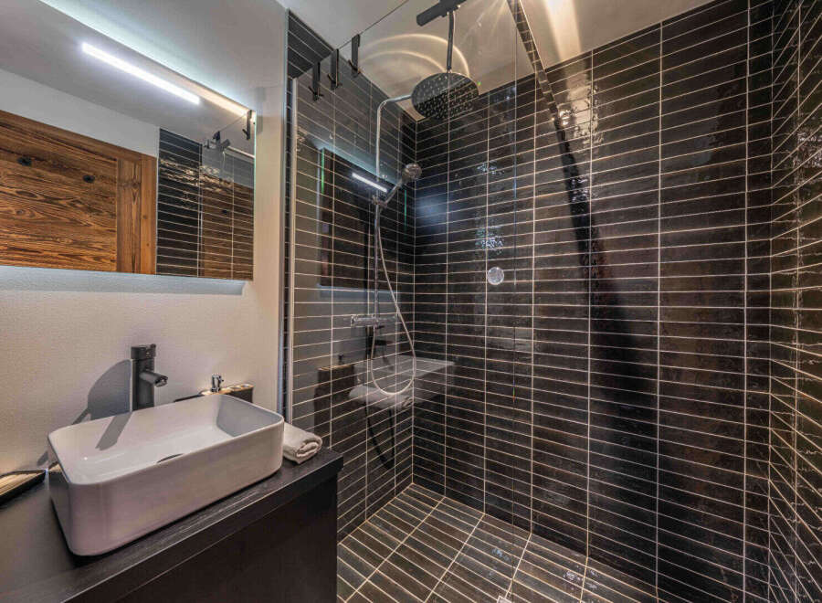 Step into luxury with this stunning bathroom! Featuring sleek black tile, a modern sink, and a spacious shower, this space is designed for ultimate relaxation.