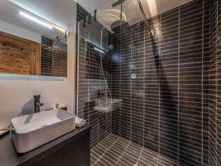 Step into luxury with this stunning bathroom! Featuring sleek black tile, a modern sink, and a spacious shower, this space is designed for ultimate relaxation.