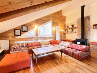 This stunning property boasts a unique, cozy living space with exposed wooden beams and walls, creating a warm and inviting atmosphere.