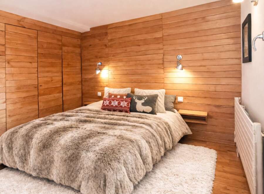 This cozy bedroom features a stunning wooden wall and a plush, inviting bed, creating a warm and rustic ambiance.