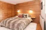 This cozy bedroom features a stunning wooden wall and a plush, inviting bed, creating a warm and rustic ambiance.
