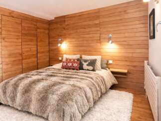 This cozy bedroom features a stunning wooden wall and a plush, inviting bed, creating a warm and rustic ambiance.