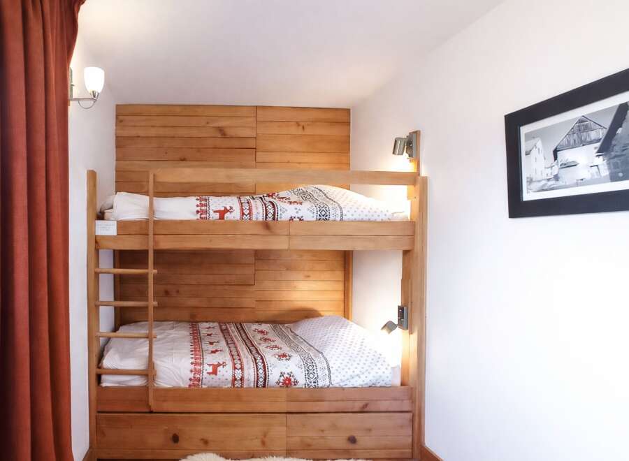 This cozy bedroom features a custom-built wooden bunk bed, perfect for accommodating guests or family members.