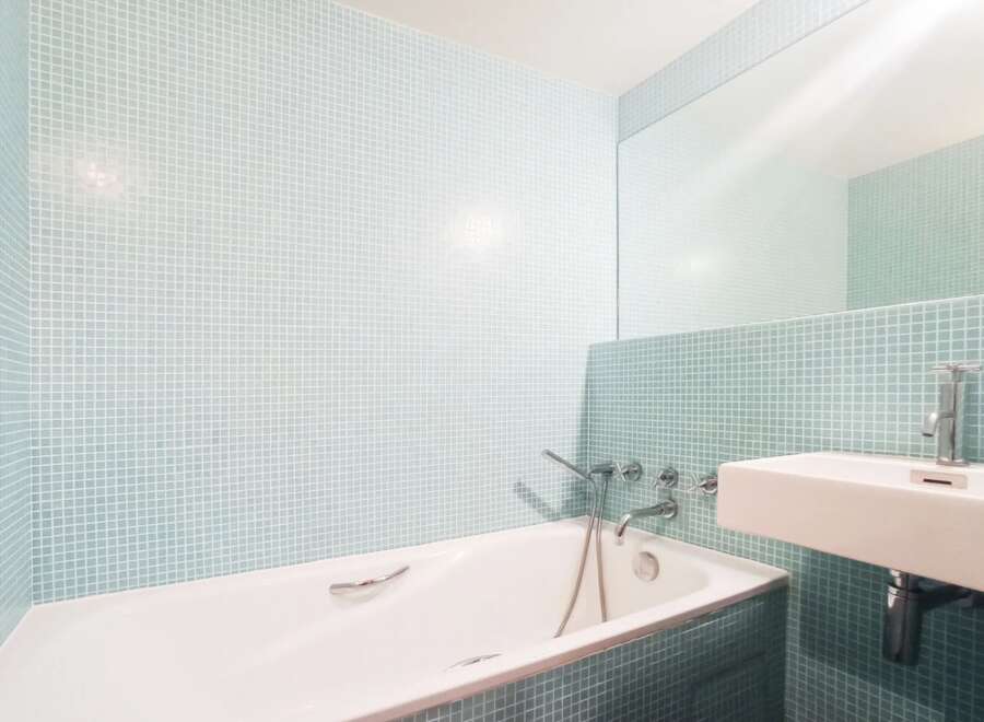 This modern bathroom features a sleek design with a bathtub and a sink.