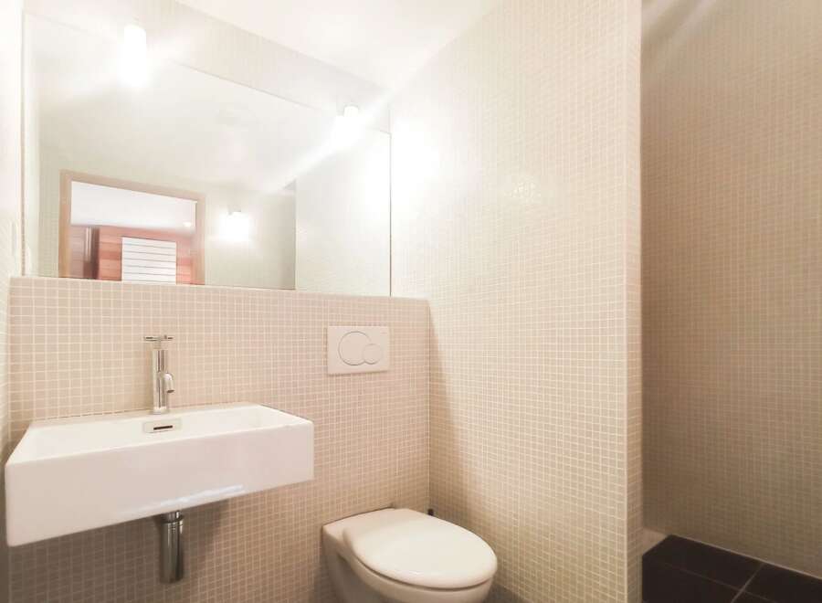 This modern bathroom features a sleek, minimalist design with a floating sink and a clean, white toilet.
