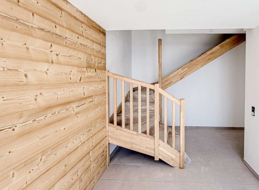 This stunning property features a beautifully crafted wooden staircase and accent wall, creating a warm and inviting atmosphere.