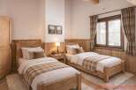This cozy bedroom features two twin beds with wooden frames, perfect for a comfortable stay.