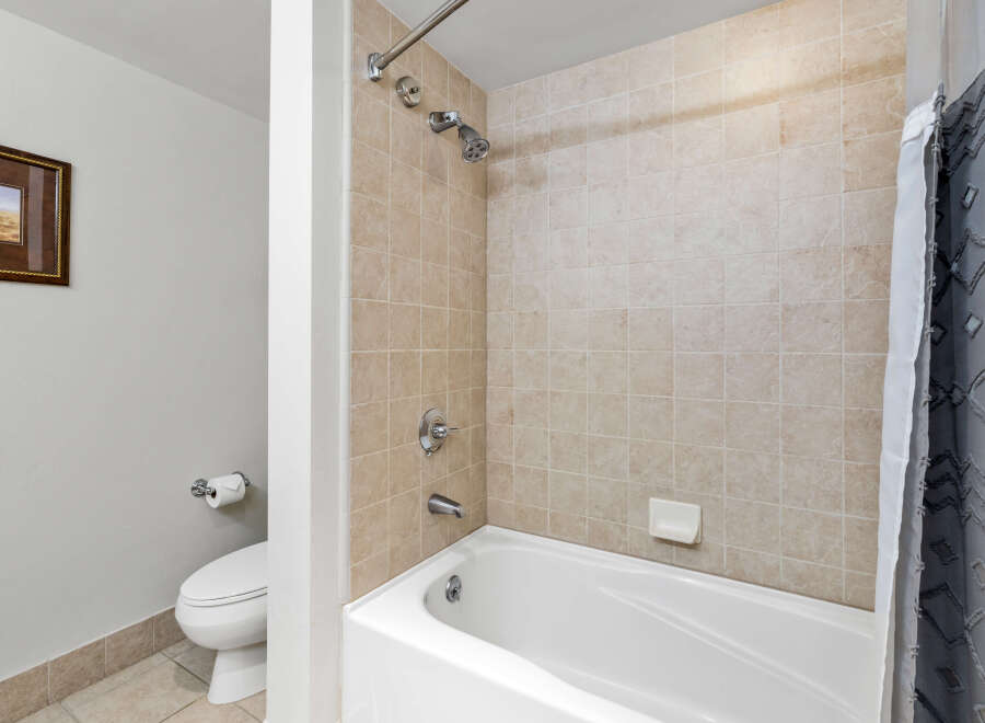 This bathroom features a clean and modern design with a white bathtub and beige tiled walls.